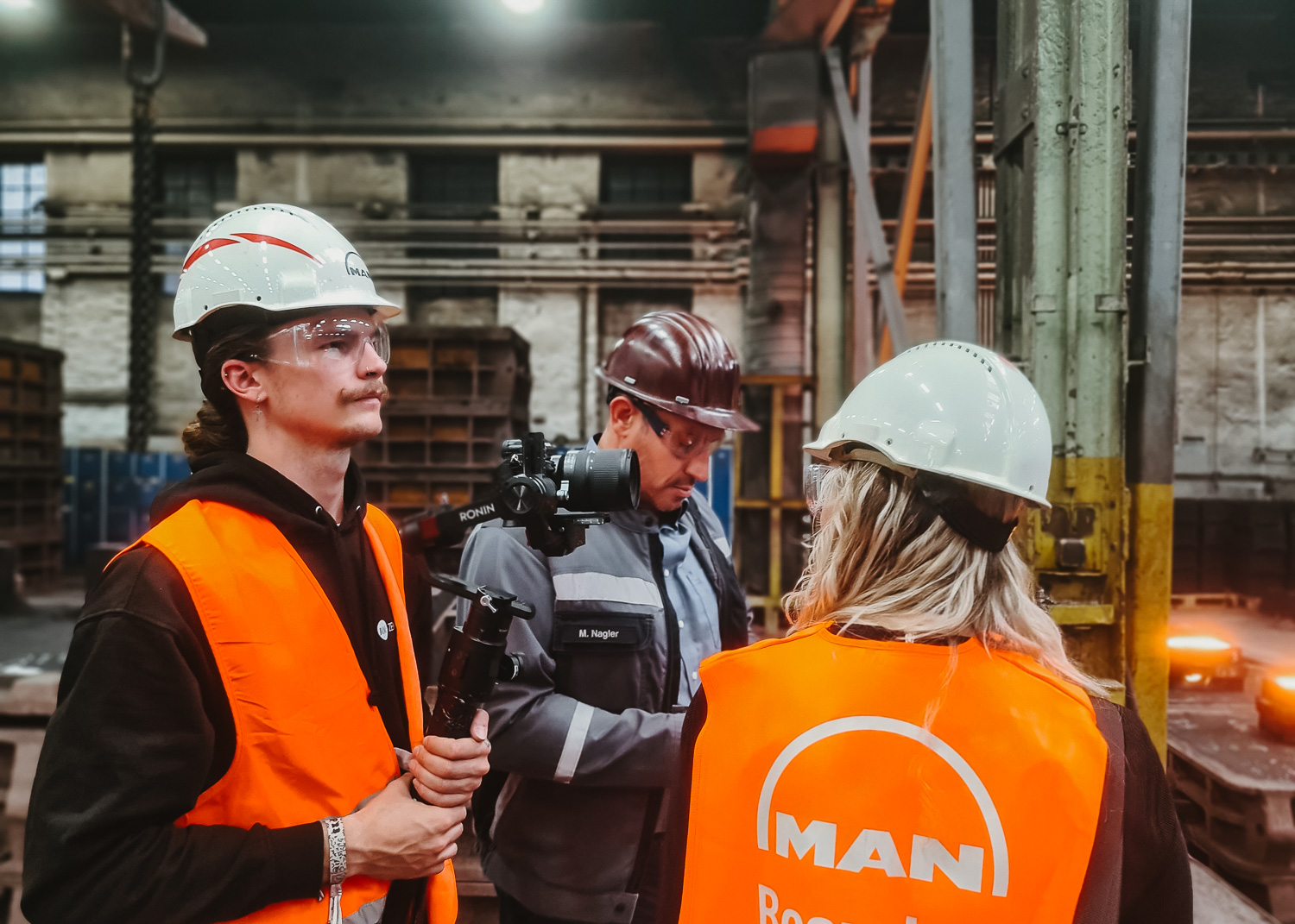 Filmteam mit Sicherheitsausrüstung und Kamera in der Gießerei der MAN Energy Solutions SE
