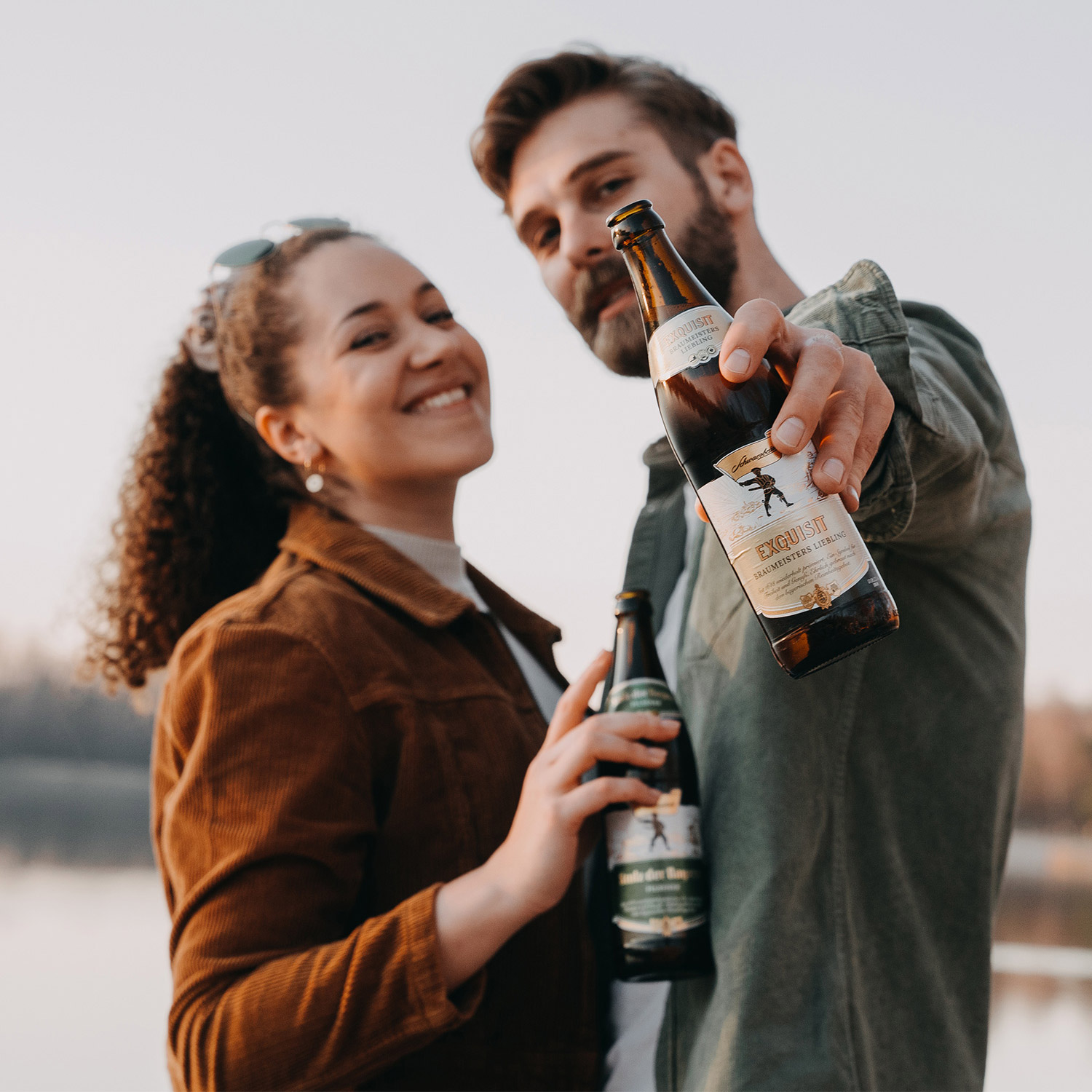 Zwei sympatisch lächelnde Personen mit Bier in der Hand
